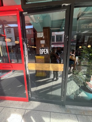 Glass door with black frame. Push from left to open.