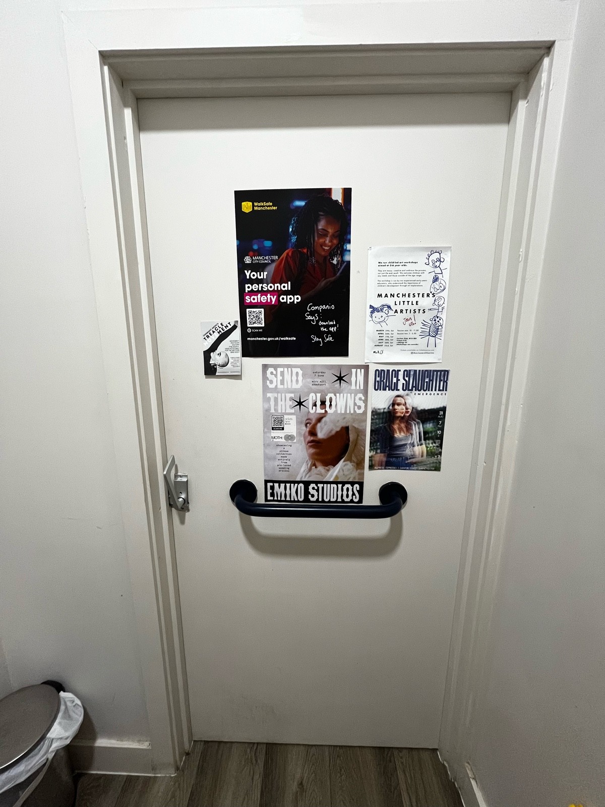Back of door. Black grabrail in centre. Push from metal handle on left to open.