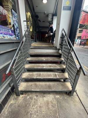 Steps lead up to entrance landing. Silver handrails on both sides.