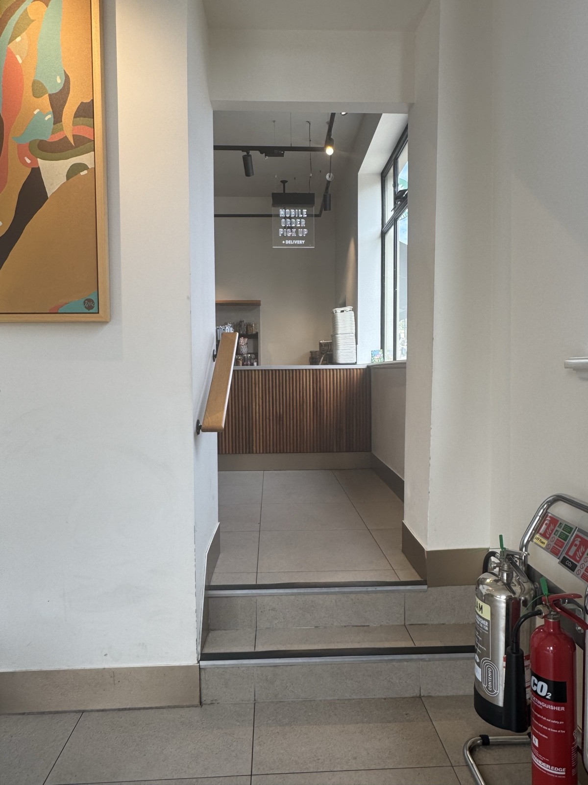 Handrail is provided along the steps leading to the ordering counter, offering support for those with mobility difficulties.