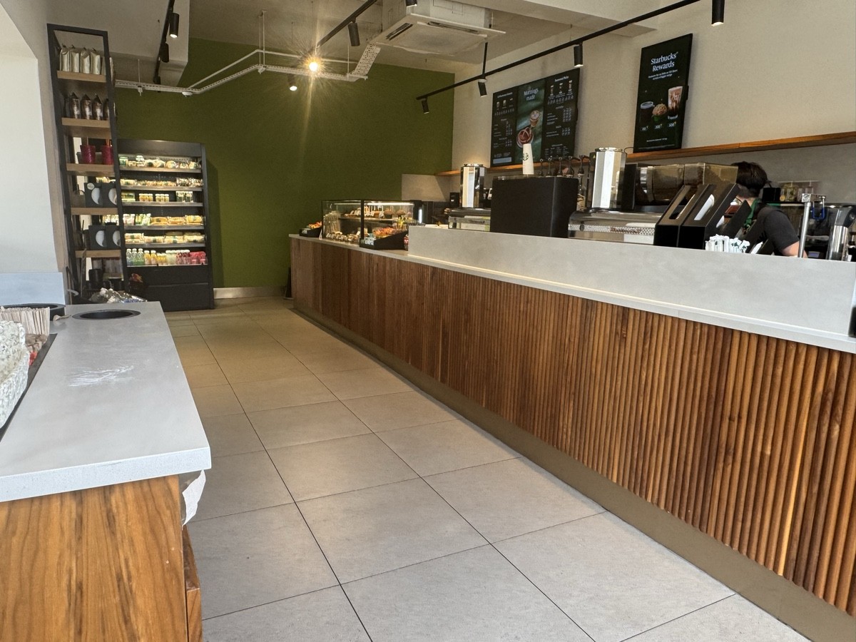 Ordering and waiting area with a mild food aroma; also a kitchen space. Well spaced, good counter height, with image-based and digital menus on walls.