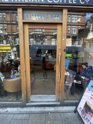 Glass door with brown wooden frame ahead. Push silver metal handle from right to open.