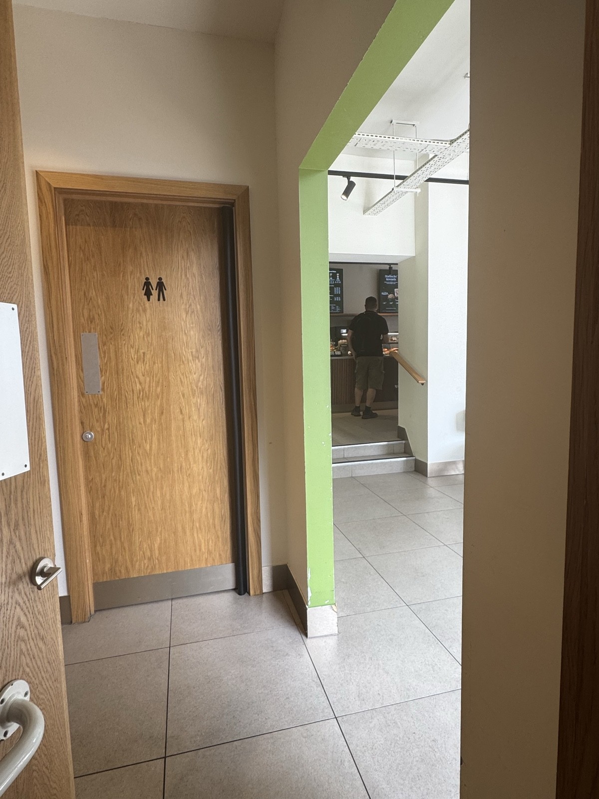 A small non-accessible toilet is located opposite the accessible one, with a push door and clear signage displayed on the outside.