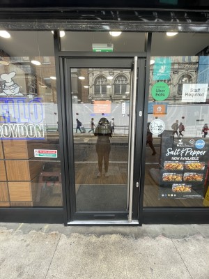 Glass door with black frame ahead. Push silver metal handle from right to open.