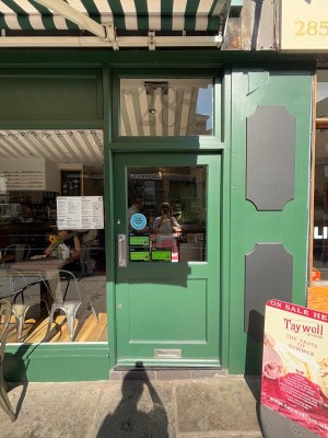Green wooden and glass door ahead. Push silver metal handle from left to open.