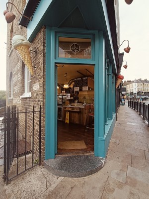 Glass door with green wooden frame, push from right to open.