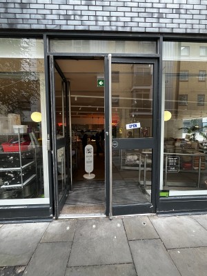 Glass doors with black frame ahead. Push from metal handles in centre to open.