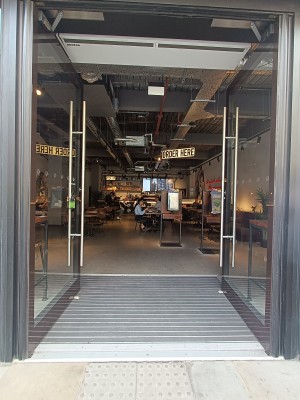 Glass doors with black, frames ahead. Push silver handle in middle to open.