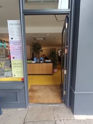 Glass door with grey, wooden frame. Push golden handle on left to open.