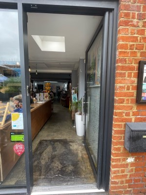 Glass door with metal frame around. Push handle on left to open.