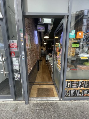 Glass door with grey frame ahead. Push silver metal handle on left to open.