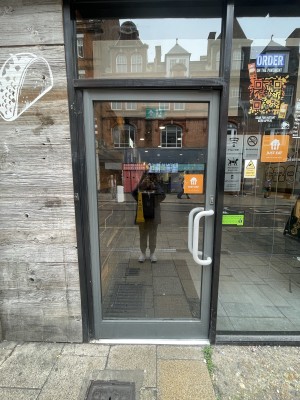 Glass door with grey frame ahead. Push white handle from right to open.