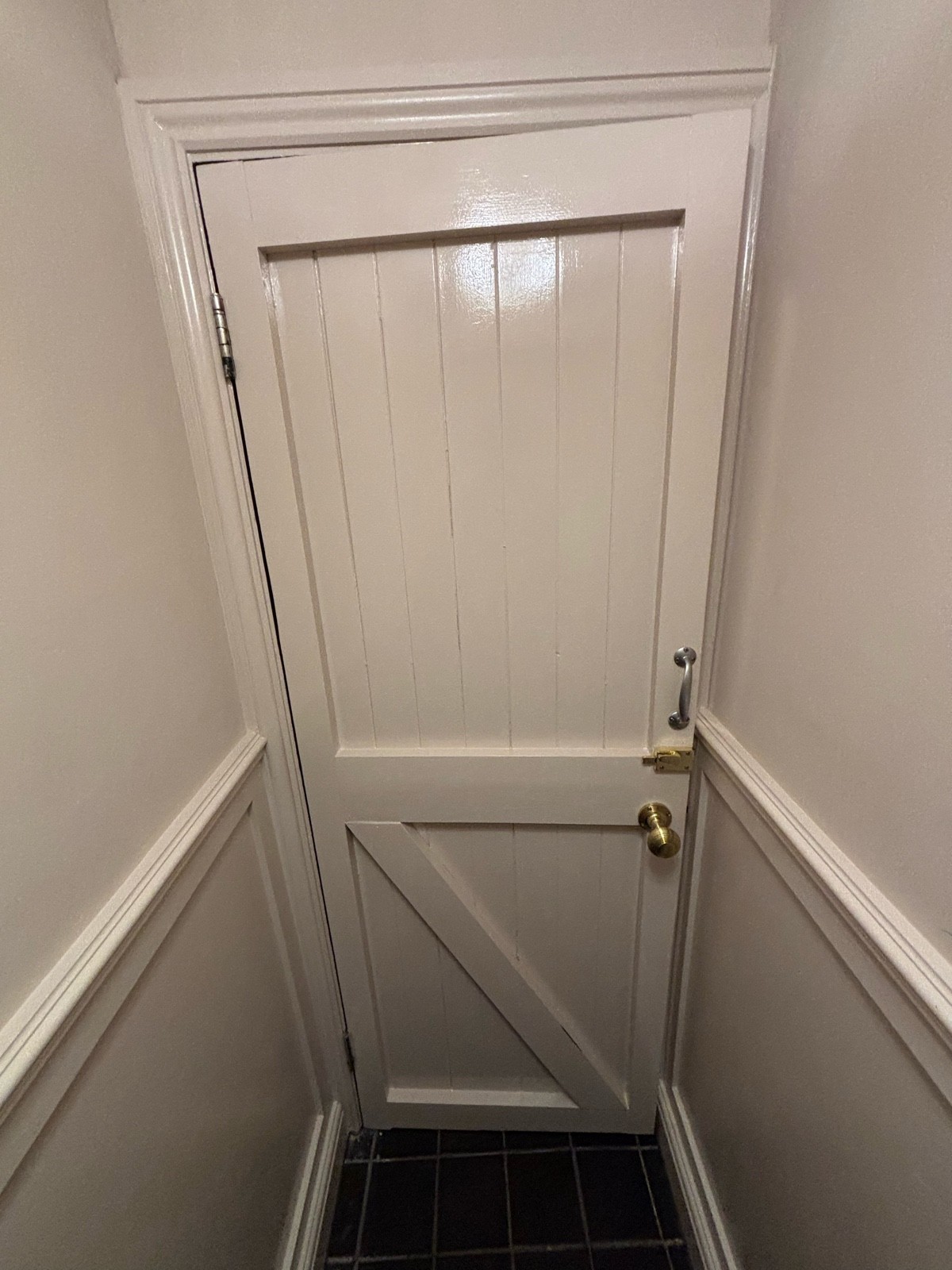 Back of door ahead. White door. Brass handle on right, lock above. Metal handle above. Turn brass handle and pull to open.