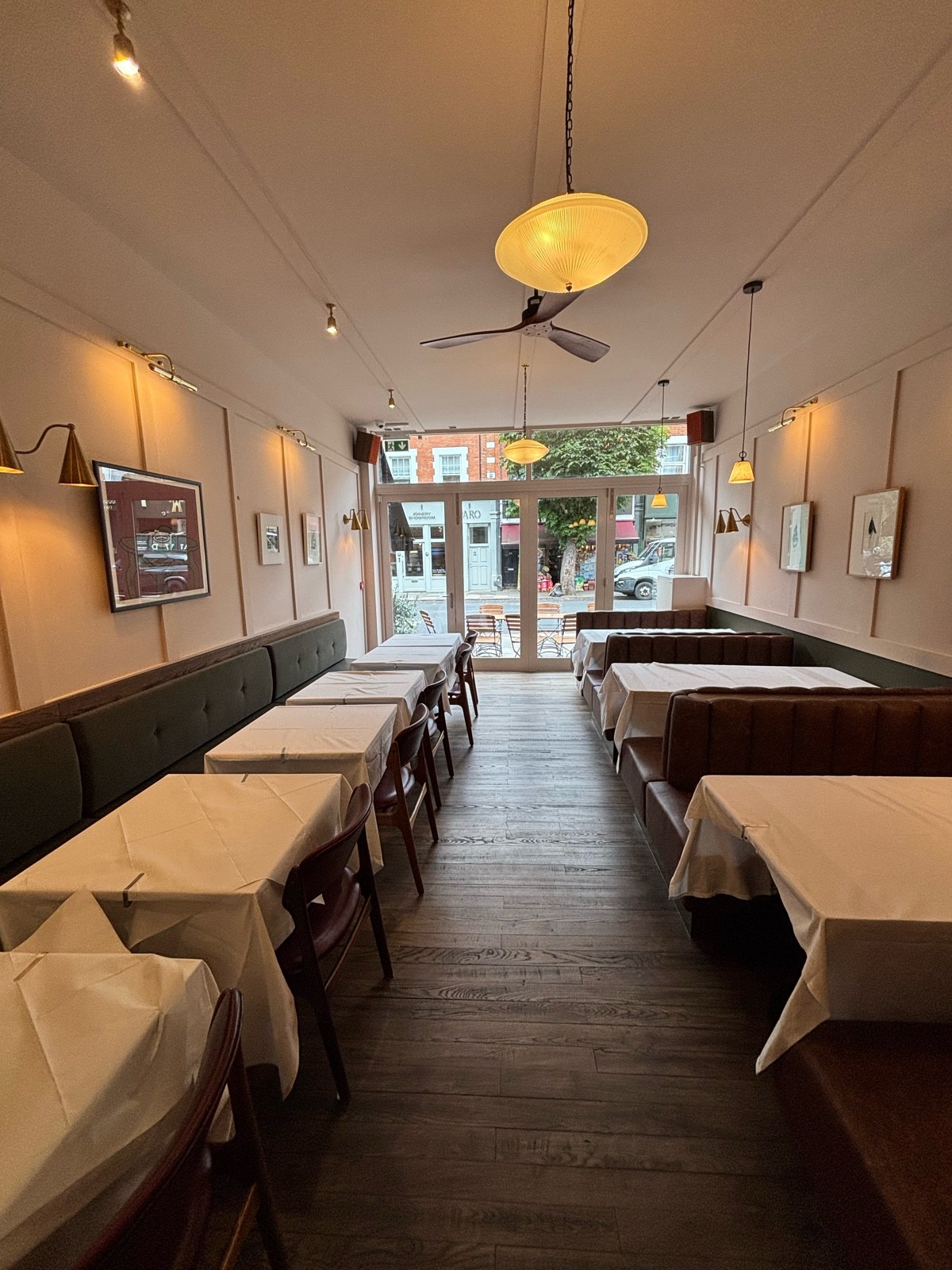 From divider facing straight. Booths along right. Half booth with tables and chairs along left.