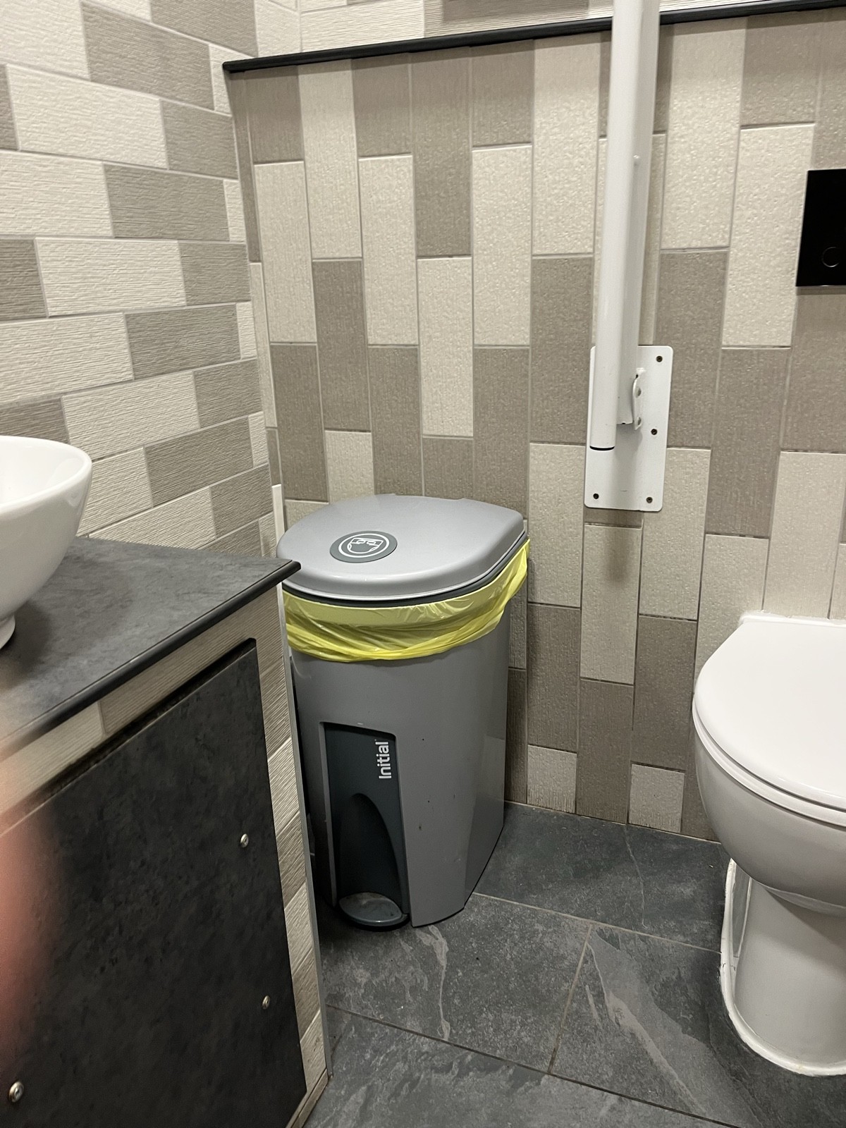 A photo showing the space to the left of the toilet which is obstructed by both the sink and a nappy bin