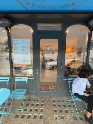 Glass door with grey frame. Pull via handle on left to open.