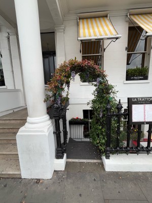 From sidewalk facing venue. Open archway with gate ahead. Push gate from right to open.