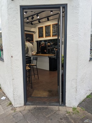 Glass door with grey frame. Push from grey handle on left to open.