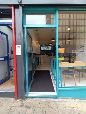 Glass door with blue, metal frame. Push handle on right to open.