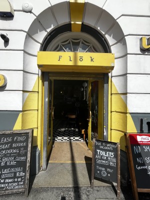 Glass doors with yellow frame ahead. Push from metal handles in centre to open.