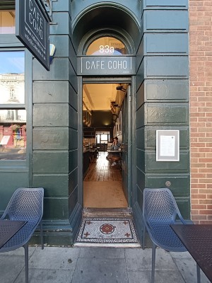Glass door with green, wooden frame. Push from left to open.