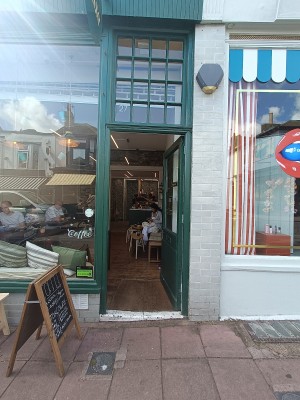 Glass door with green, wooden frame. Push from left to open.