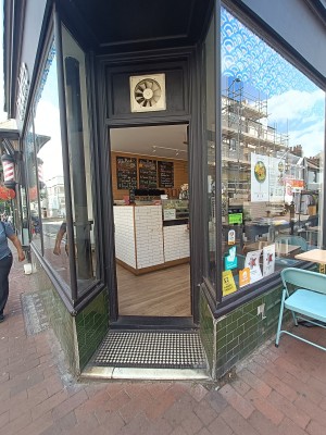 Glass door with black, wooden frame. Push from left to open.