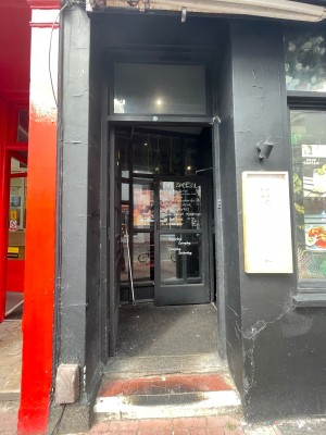 Glass paneled door with black frame. Push on right to open.