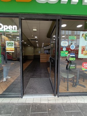 Glass door with black, wooden frame ahead. Push from black, handle on left to open.