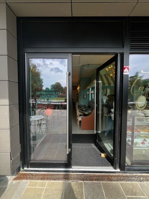 Glass doors with black frame ahead. Push from metal handles in centre to open.