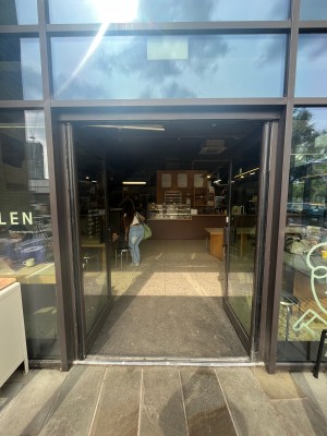 Glass doors with brown, metal frame ahead. Push from middle to open.