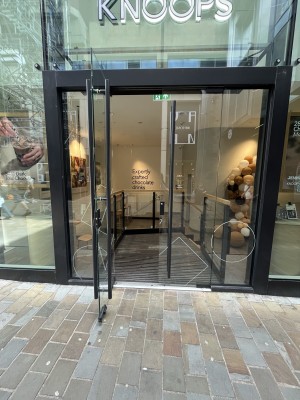 Glass doors with black frames. Pull handle in center in to open.
