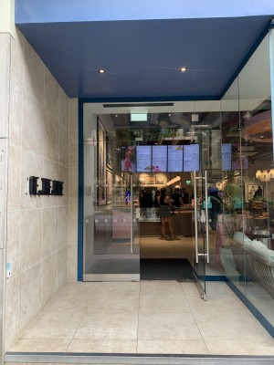 One step to doorway. Doorbell on left wall. Glass door ahead, push on middle to open.