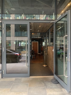Glass doors with black frame. Push middle to open. Ramp and small bump at entryway.