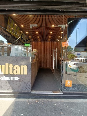 Glass door with silver metal handle. Push from left to open.