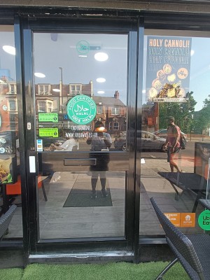 Glass door with black, metal frame. Push handle from left to open.
