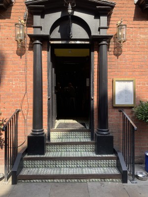 Black door. 4 steps to access. Handle on right, push to open.
