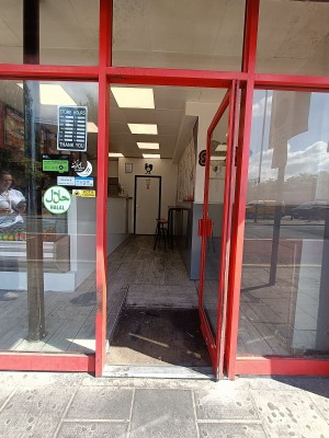 Glass door with red, metal frame ahead. Push from handle on left to open.