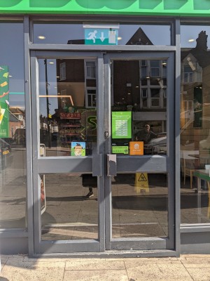Glass doors with grey frame and grey handles. Push from centre to open.