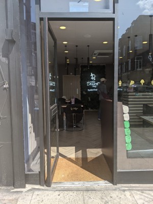 Glass door with grey frame and grey handle. Push from right to open.