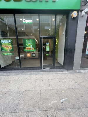 Black framed glass door with metal handle on left. Pull to open.