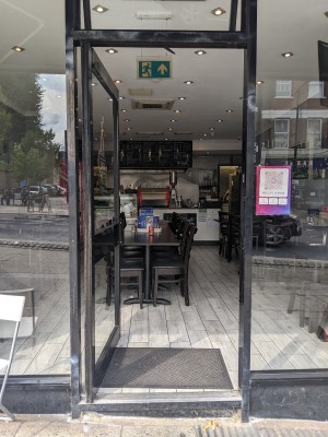 Glass door with black frame and black handle. Push from right to open.