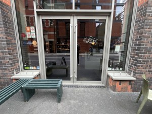 Glass door with silver frame and silver handles. Pull from centre to open.