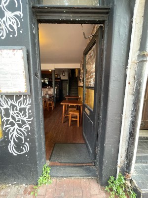 Glass paneled door with black frame. Push on left to open.