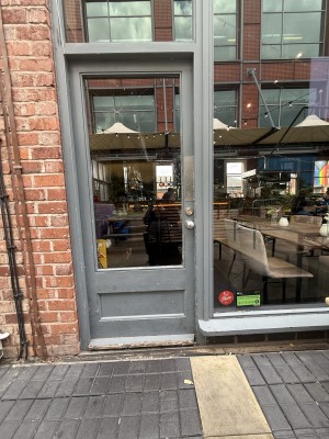 Grey glass door. Metal knob on right. Push to open.