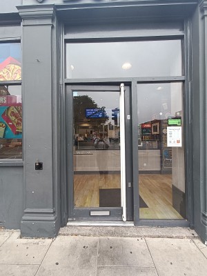 Glass door with white metal handle on right. Push to open.