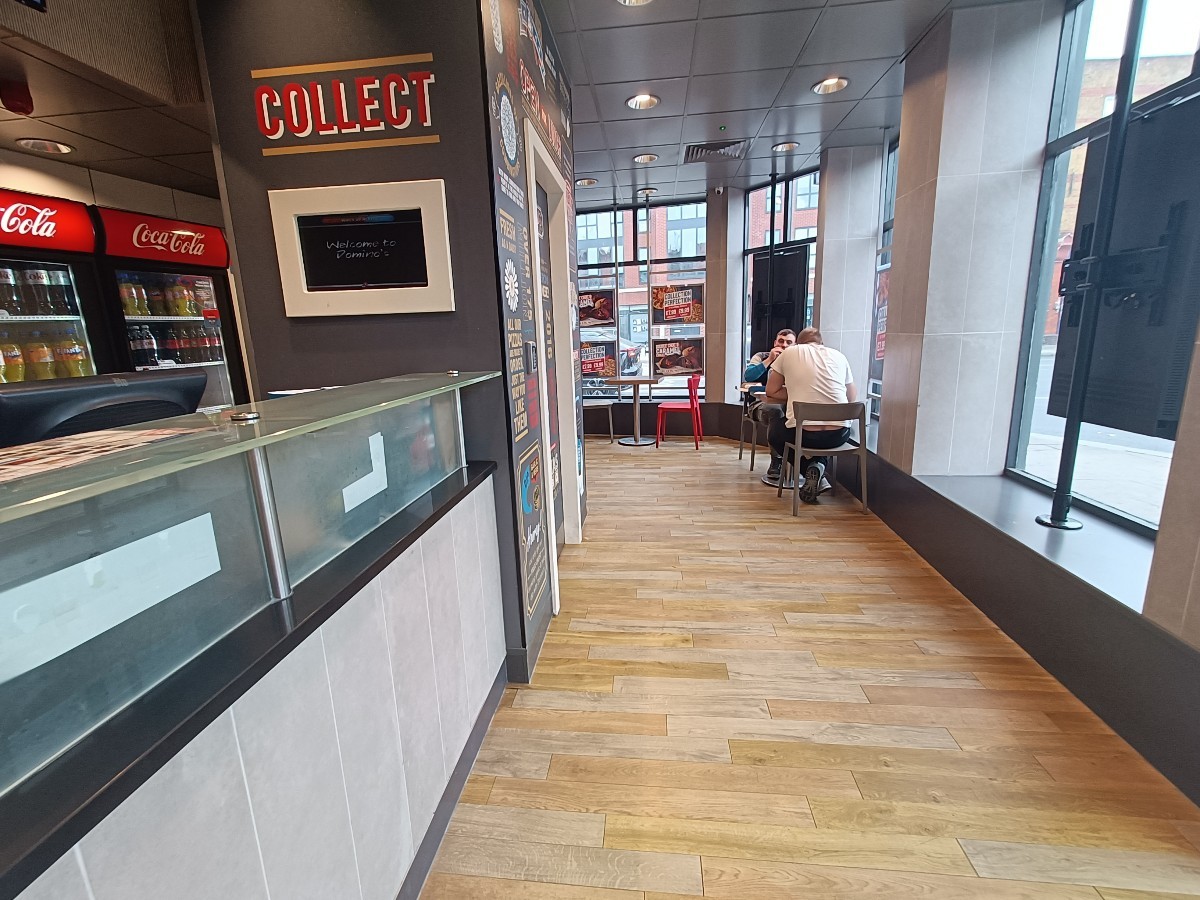 From entrance, facing right. Counter along left. Wall divider behind. Tables and chairs along back right.