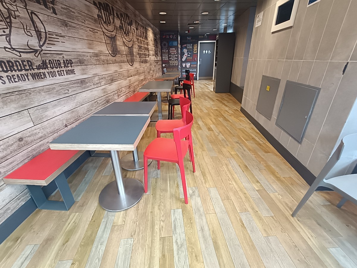 From tables and chairs, facing left. Half-booths and chairs along left. Bin at back right.