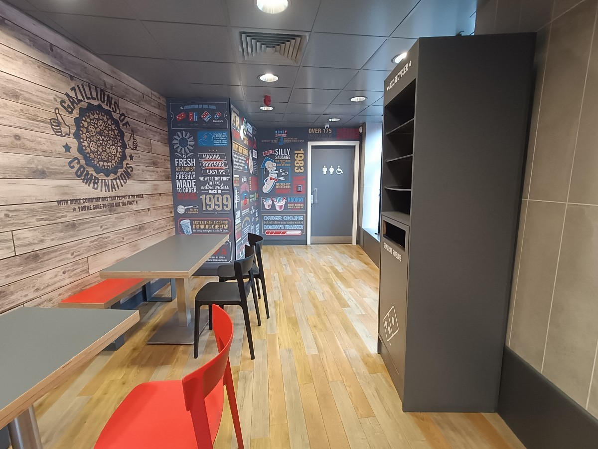 From bin, facing straight. Half-booth and chairs along left. Bin on right. Bathroom at back right.