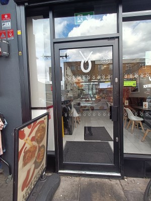 Glass door with black, metal frame. Push from right to open.
